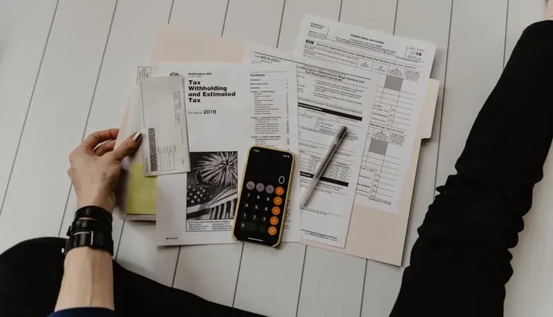 Secretária com documentos fiscais e computador portátil